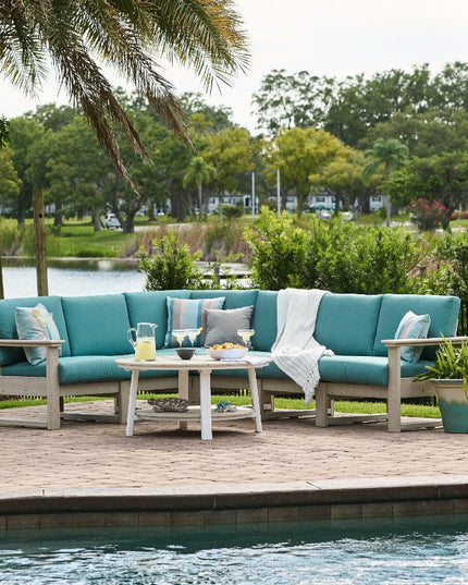 Turquoise outdoor sofa set on a wooden deck by a pool with a scenic background.