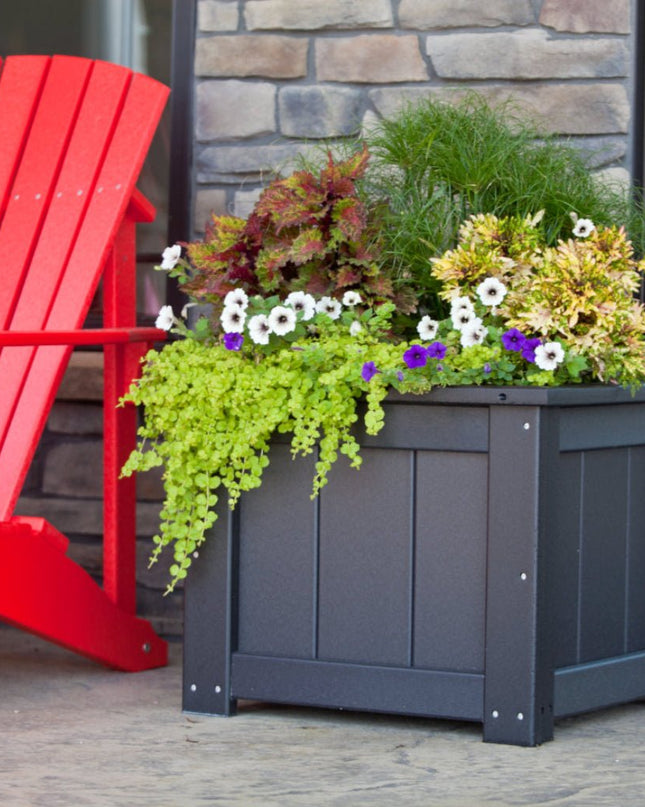 LuxCraft Poly 24 inch Square Planter featured in Black next to LuxCraft Deluxe Adrirondack Chair.